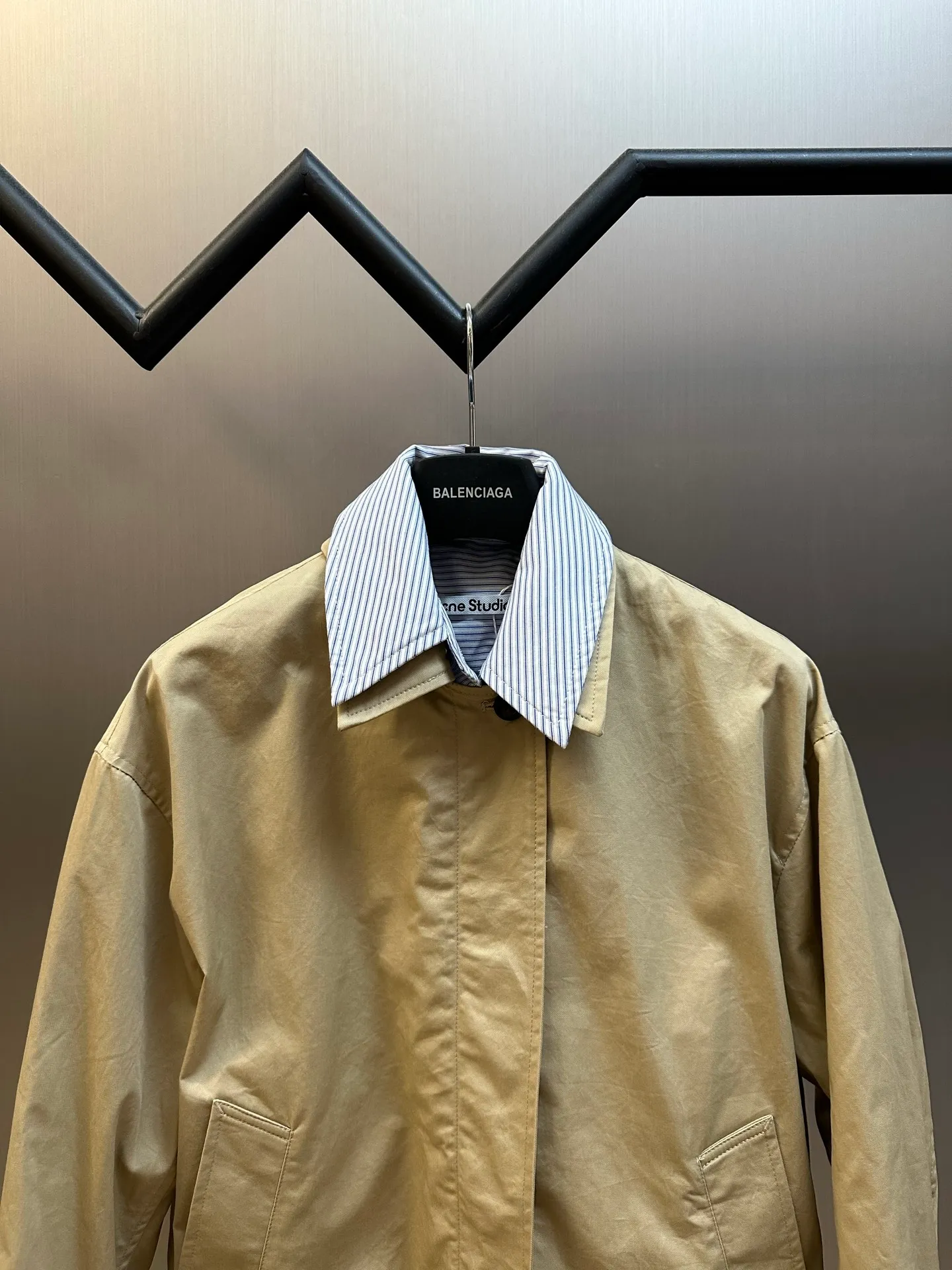 Ac Hot Sale genuine two-piece jacket. The main body is made of high-density twill cotton poplin. It has been processed by pre-shrunk washing process. The cloth surface is smooth and clean, with a matte and soft workwear texture. The stiffness is just right. The short version can be held up three-dimensionally and is not easy to collapse and wrinkle. It is suitable for daily commuting and outdoor use. The inner shirt is made of yarn-dyed blue and white striped cotton. The yarn-dyed stripes have clear texture and will not turn white or smudged after washing. The fabric surface is breathable and dry, and the collar and cuffs are folded and exposed to form contrasting color layers. The difficulty of the whole piece lies in the combined sewing of two fake pieces. The shirt collar and jacket collar are double-stitched and seamed. The collar corners are shaped and hemmed, and the folding shape is neat and will not collapse and curl. The placket adopts a double-layer structure of zipper + hidden buckle windproof fabric. The inner and outer layers of fabric are aligned and sewn together, and the wiring is even and fine. There are adjustable tabs on both sides of the hem, which can be freely tightened to suit different styles. The back printing adopts embossed relief technology, which blends into the fabric and is low-key and unobtrusive. The zipper is made of nylon zipper with metal teeth. The teeth are polished smoothly and will not get stuck after repeated pulling. The zipper headband has brand engraved details. The buttons are divided into two systems: the outer part is made of horn dark brown resin buttons with natural texture and high-end matte texture; the inner shirt is equipped with Cream White pearlescent four-eye buttons, echoing the blue and white striped fabric. size：xs s m l
